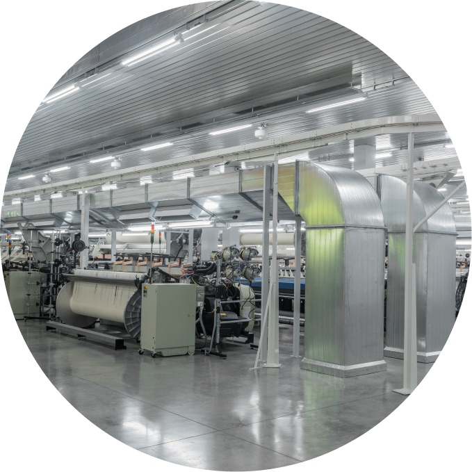 Wide view of industrial textile machinery inside a spacious, well-lit factory with polished concrete floors.